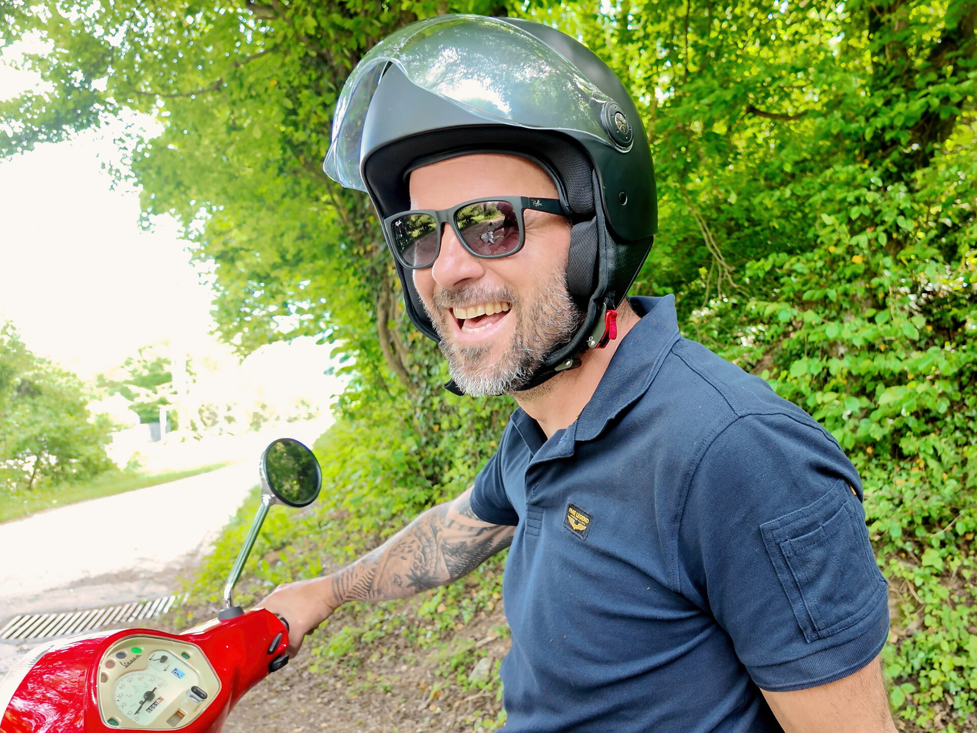 Lachende rijder op een rode Vespa geniet van het avontuur